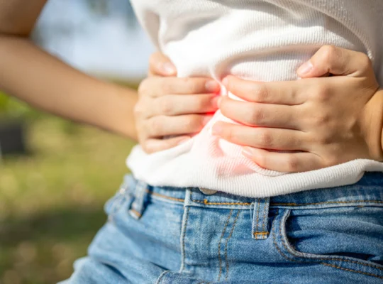 Personne tenant son abdomen avec les deux mains, exprimant une douleur abdominale typique du syndrome de l'intestin irritable (SII)