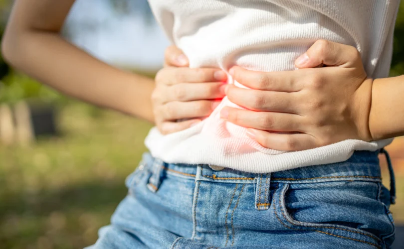 Personne tenant son abdomen avec les deux mains, exprimant une douleur abdominale typique du syndrome de l'intestin irritable (SII)